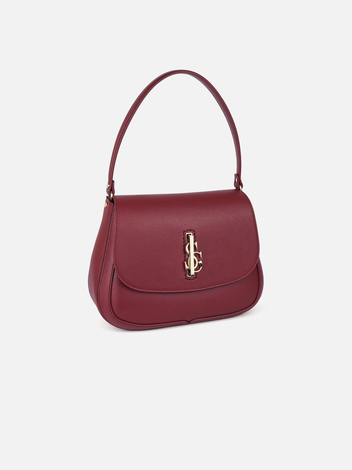 A close-up studio shot of a dark cherry-colored pebbled leather handbag with a top handle and a central gold interlocking 'JC' monogram hardware clasp. The bag is angled slightly to the right against a plain, light blue gradient background.