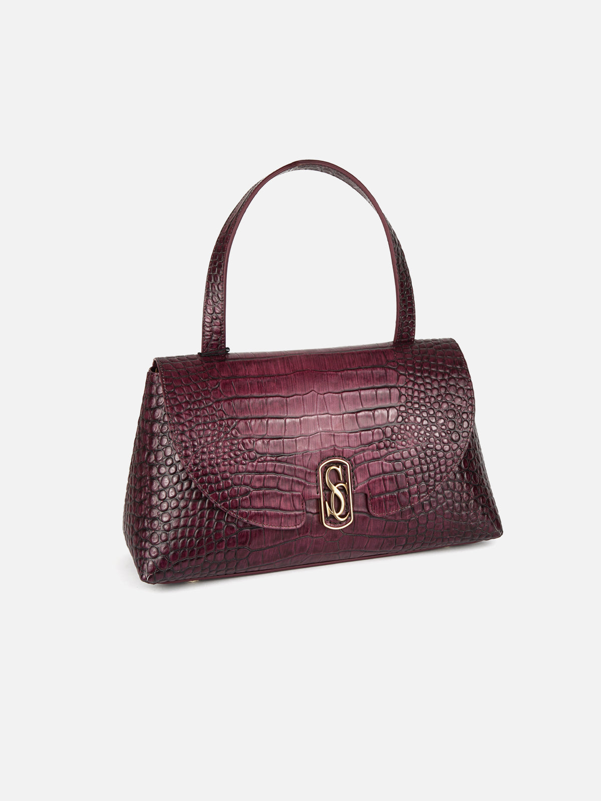 An elegant, structured top handle satchel made from deep burgundy crocodile-effect calfskin, featuring a signature gold-plated metal interlocking 'S' monogram buckle. Isolated on a light grey background.