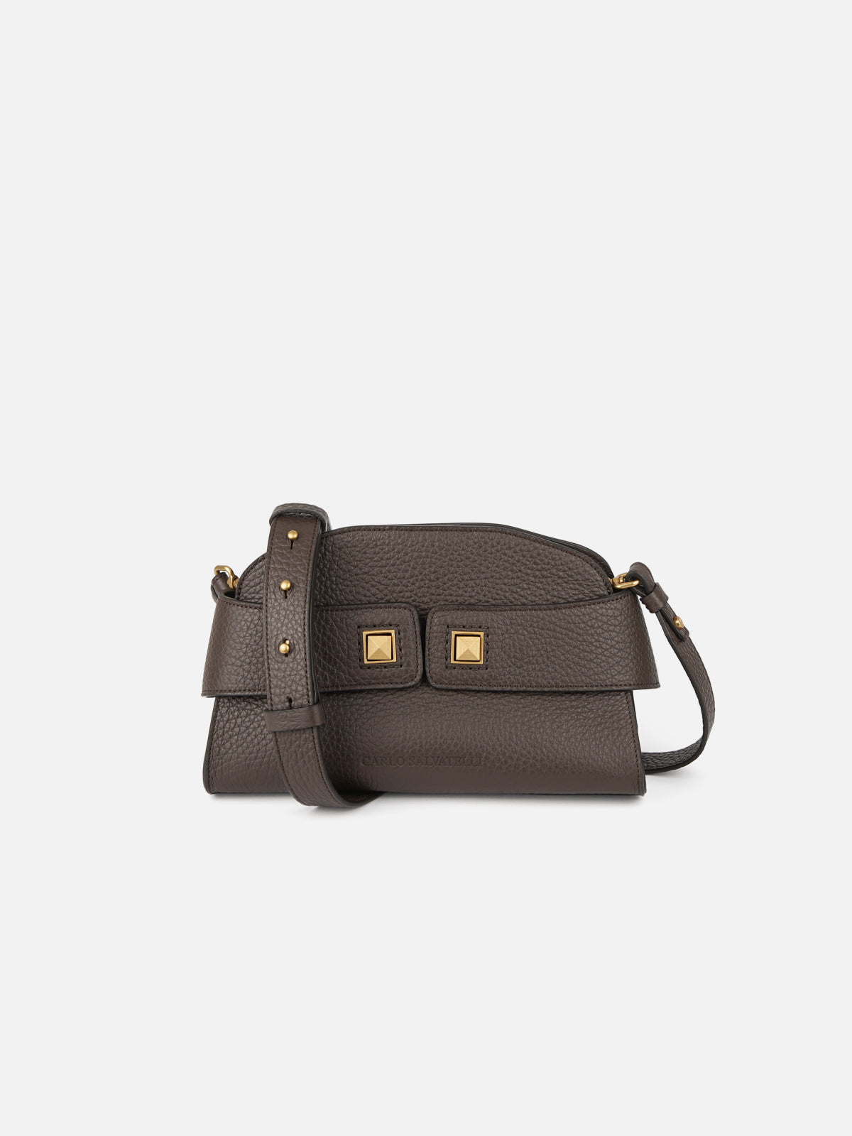 A frontal three-quarter view of a structured, dark espresso brown pebbled leather dome-shaped crossbody bag. The bag features an adjustable leather strap secured by polished gold-tone metal screw studs, and two distinct central square pyramid studs. A subtle embossed text logo is visible at the bottom center.