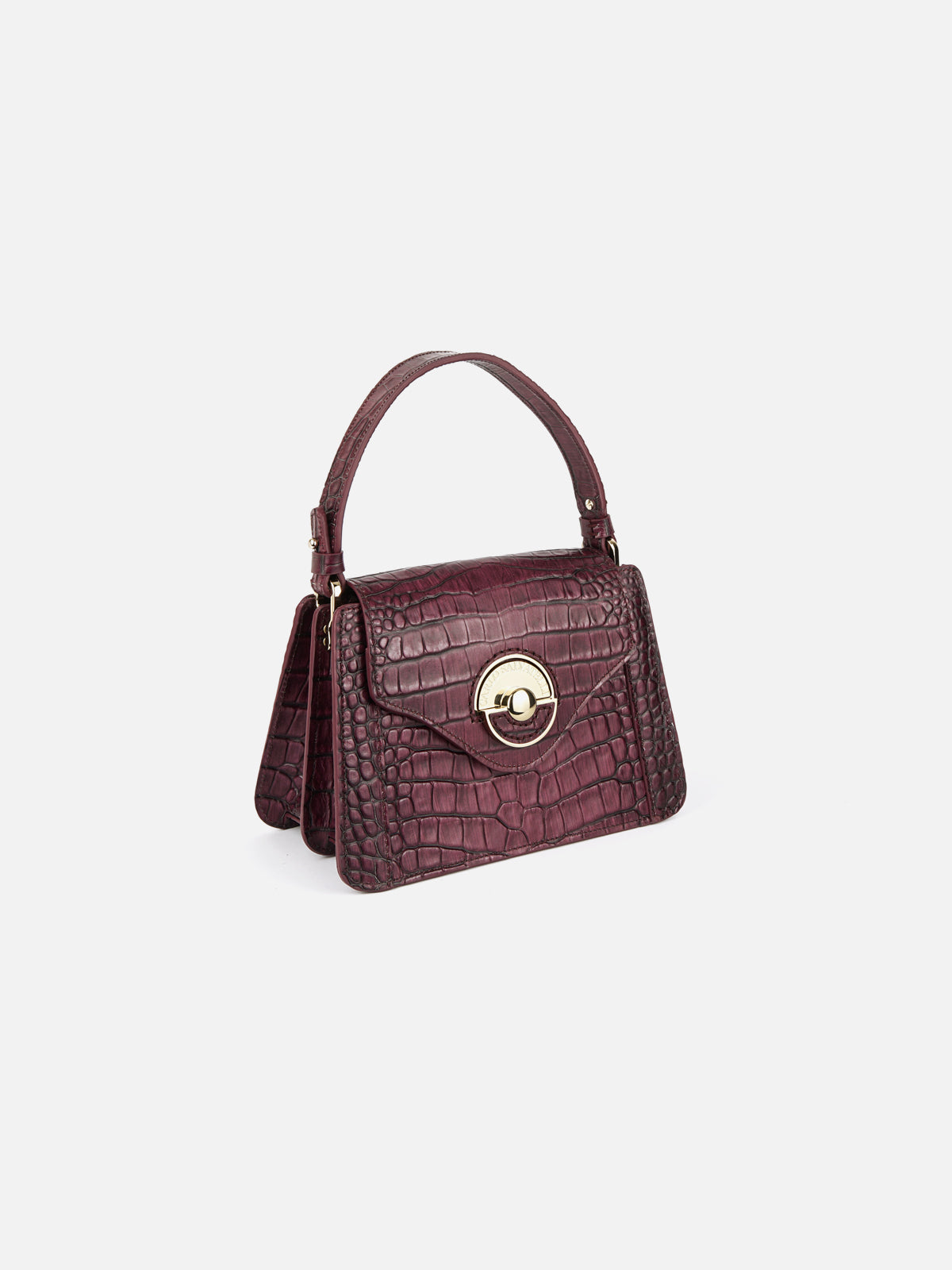 A deep magenta grained leather handbag with a distinct gold-tone hardware clasp and a structured handle, isolated on a plain white studio background.